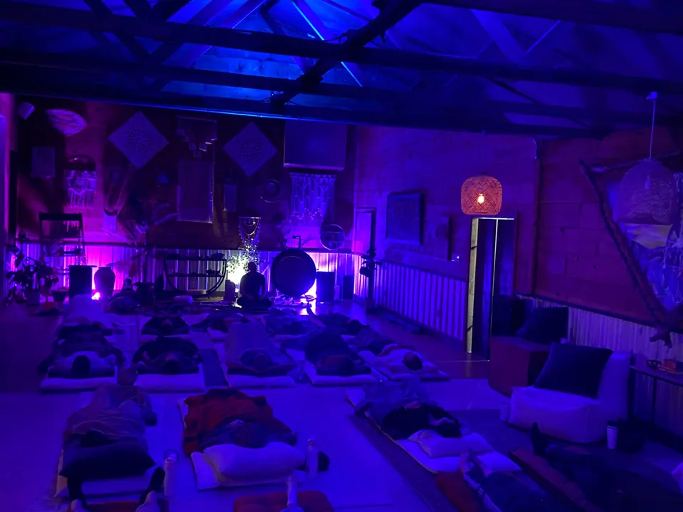 A ceremony under way in the open-air temple, guests resting on mats in blue light