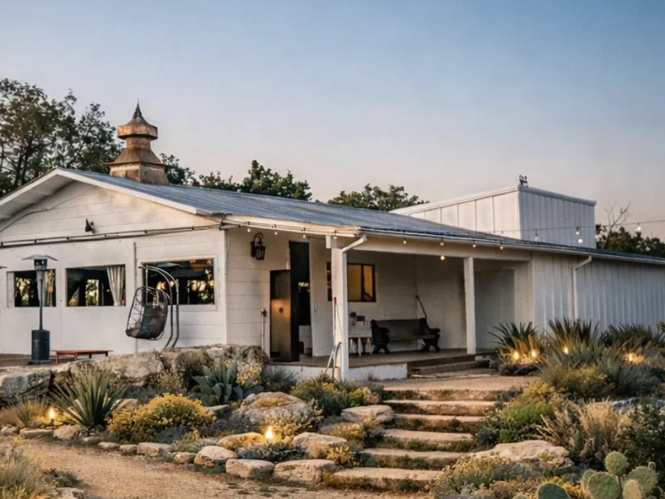 The temple at dusk &mdash; copper cupola above a covered porch, hanging chairs, and lit stone steps through the garden